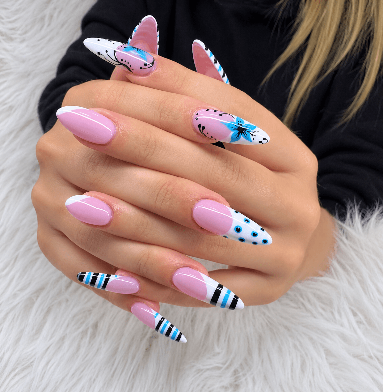 Pink nails with graphic white French tips featuring hand-painted butterflies, dots, and fine stripe accents in black and blue